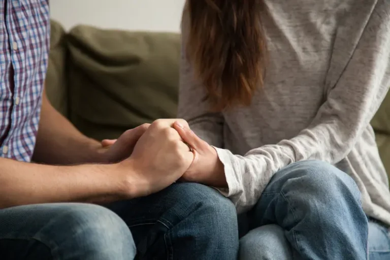 A couple on a couch hold hands while using mediation in uncontested divorce.
