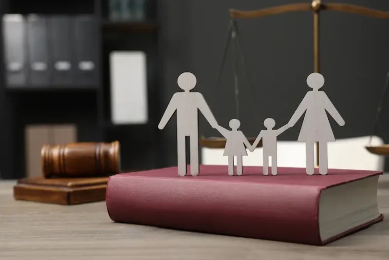 Cardboard figures of a family on top of a law book represent uncontested divorce and child custody.