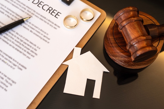 Divorce decree document with wedding rings, gavel, and paper house symbolizing asset division in affordable uncontested divorce process.