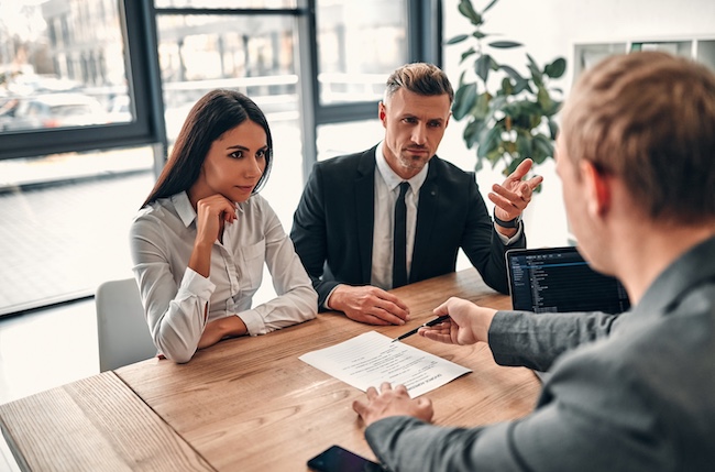 Couple consulting with a lawyer at a table, discussing affordable uncontested divorce options and paperwork.