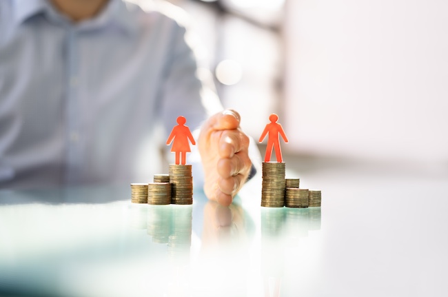Hand separating two stacks of coins with red figures symbolizing a couple, representing asset division in an affordable uncontested divorce context.