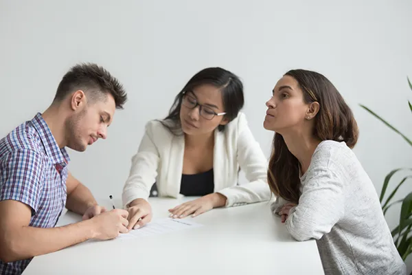 Couple discussing divorce paperwork with a lawyer in a professional setting, emphasizing the uncontested divorce process in Houston.