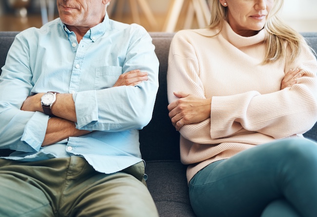 Couple sitting apart on a couch, conveying emotional distance and tension, reflecting the theme of uncontested divorce and cooperative separation.